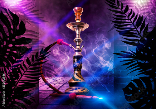 Hookah on the background of tropical leaves and a brick wall. Neon light, laser figures in smoke