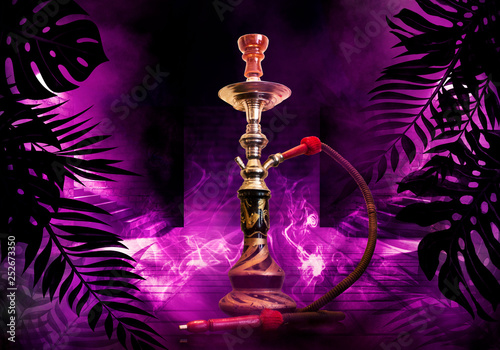 Hookah on the background of tropical leaves and a brick wall. Neon light, laser figures in smoke