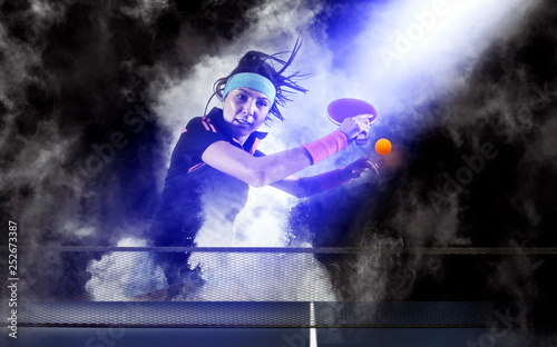 Woman playing ping pong on dark smoke background