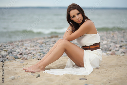 Gorgeous dark-haired girl in dress on sandy beach