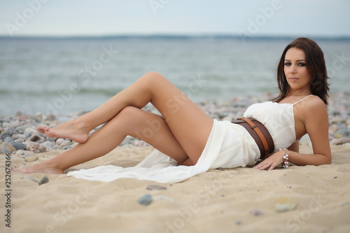 Gorgeous dark-haired girl in dress on sandy beach