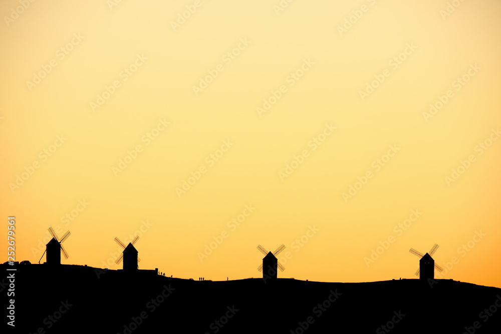 Silhouettes of the Mills of La Mancha and people a sunset.