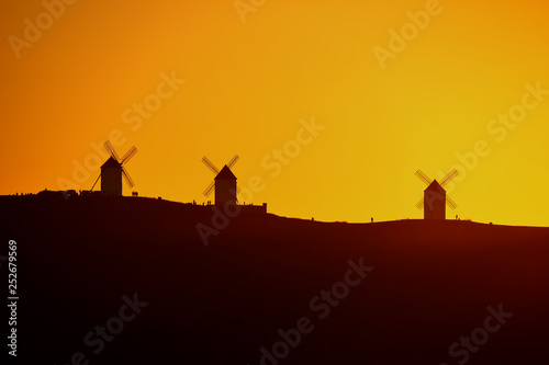 Silhouettes of the Mills of La Mancha and people a sunset.