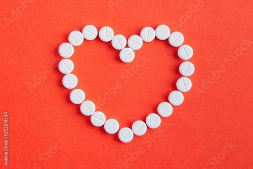 medicine, healthcare and pharmacy concept - pills and of drugs in shape of the heart and heart rhythms.