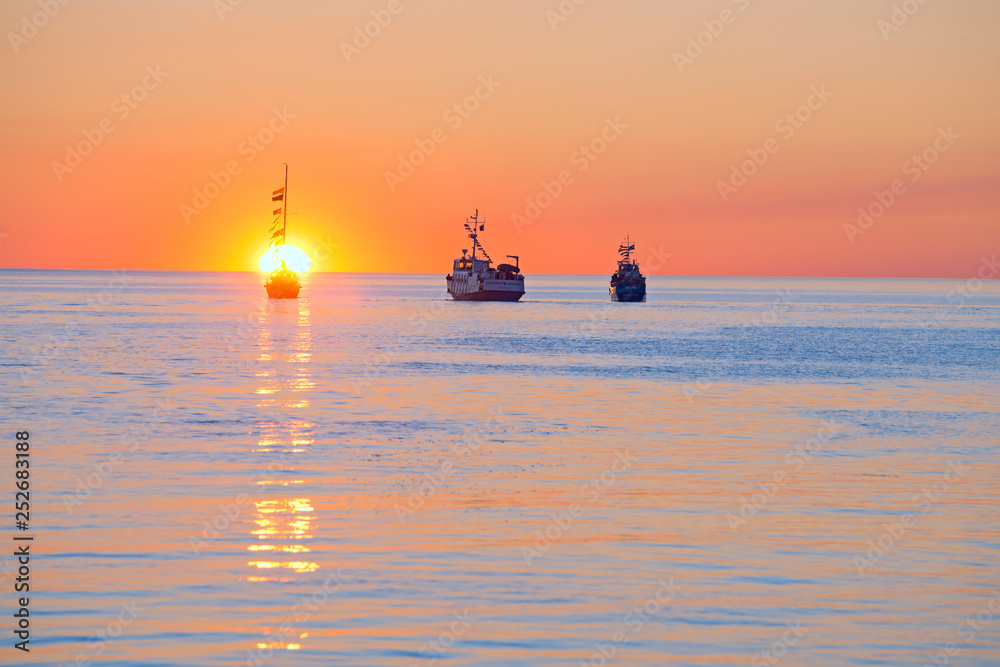 Fototapeta premium At sunset, ships in the White sea pay tribute to the dead sailors.