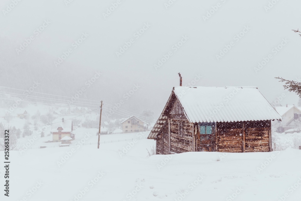 rural mountain house during snow fall. 
