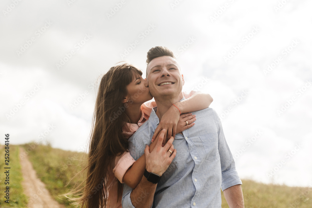 Loving young couple kissing and hugging in outdoors. Love and tenderness, dating, romance, family, anniversary concept. Loving young couple kissing and hugging in outdoors. Love and tenderness, dating, romance, family, anniversary concept.
