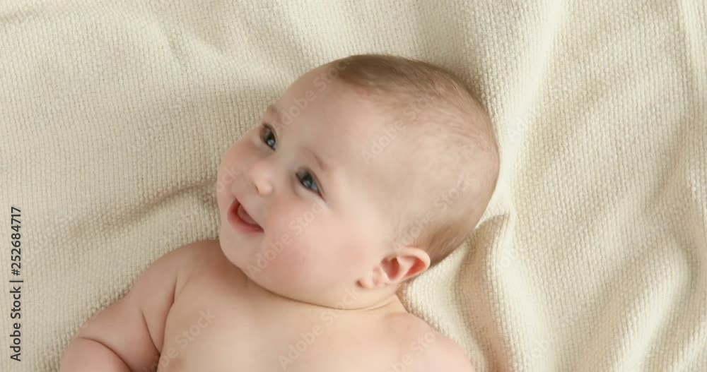 Top view of the baby looking in the camera and smiling, close up 4k shot. A cute little baby is look and smile. Babyboy looks around and smiles and laughs, view drom above Top view of the baby looking in the camera and smiling, close up 4k shot. A cute little baby is look and smile. Babyboy looks around and smiles and laughs, view drom above