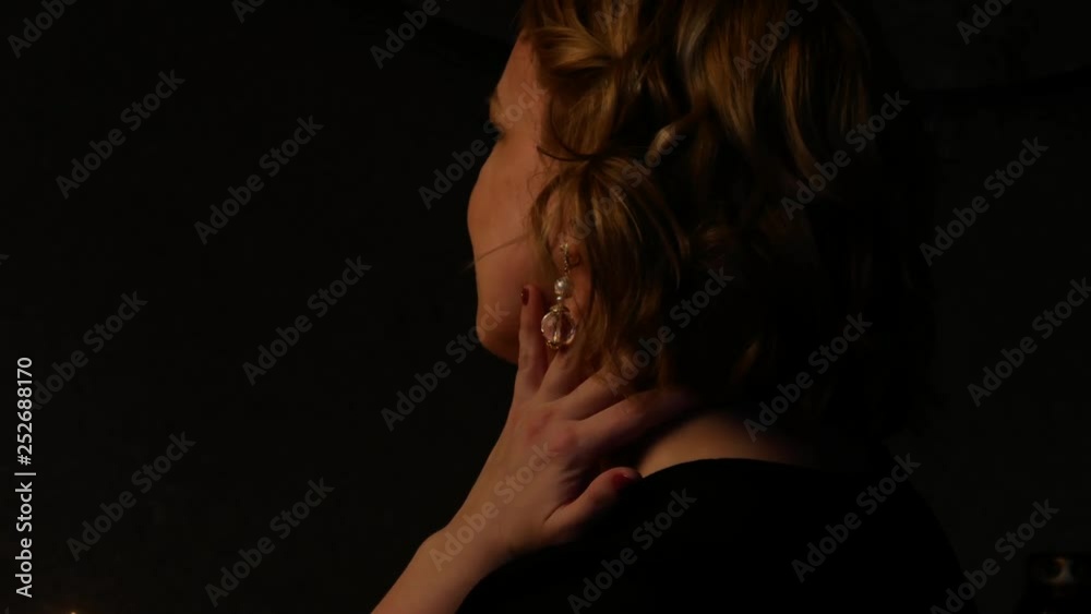 A middle-aged woman in the Catholic Church. Candles are burning on a candlestick against a dark background. A middle-aged woman in the Catholic Church. Candles are burning on a candlestick against a dark background.