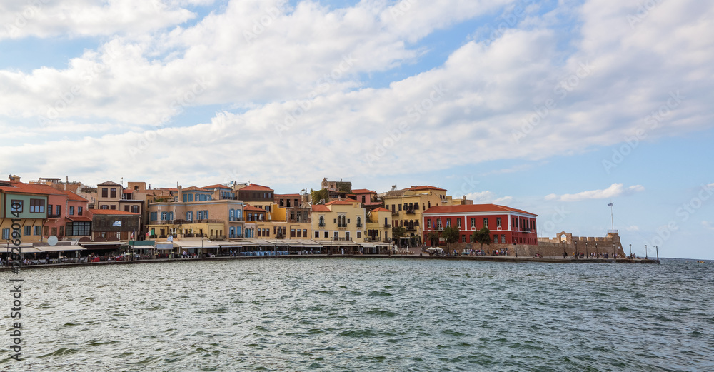 A panorama of the harbor city of Chania. View of the emarald sea, interesting landscapes, colorful houses, a coast view from the cafe. The Mediterranean Sea. A popular tourist resort in the Greece.