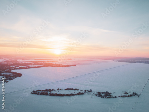 The Aerial view of snow-covered forest in time of sunny winter evening.