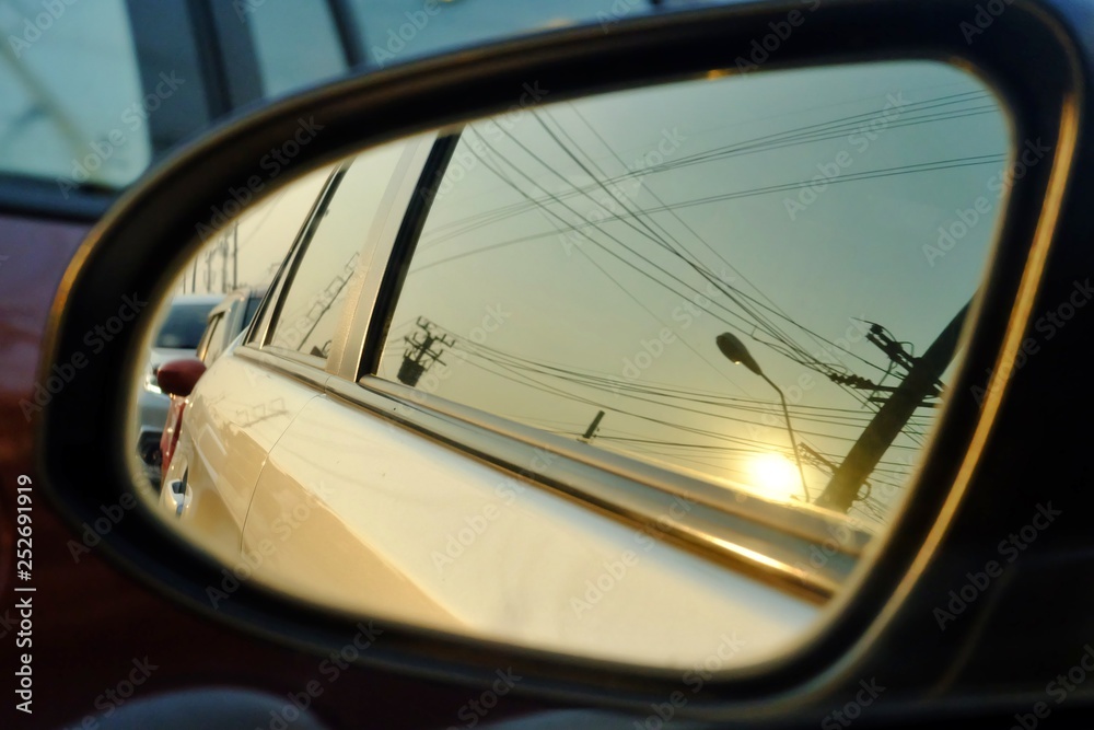 A wing mirror of a car with sun light reflection and blur street area background 
