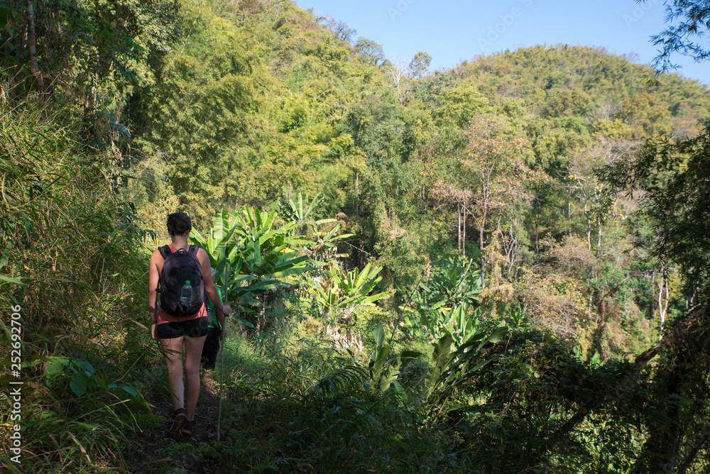 Woman walking on a trekking trail into the tropical forest