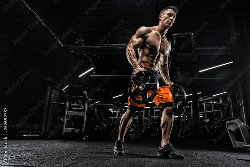 Attractive tall muscular bodybuilder doing heavy deadlifts in moder fitness center. Attractive tall muscular bodybuilder doing heavy deadlifts in moder fitness center.