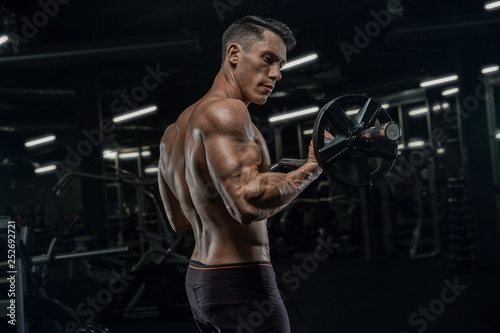 Attractive tall muscular bodybuilder doing heavy deadlifts in moder fitness center.