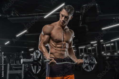 Attractive tall muscular bodybuilder doing heavy deadlifts in moder fitness center