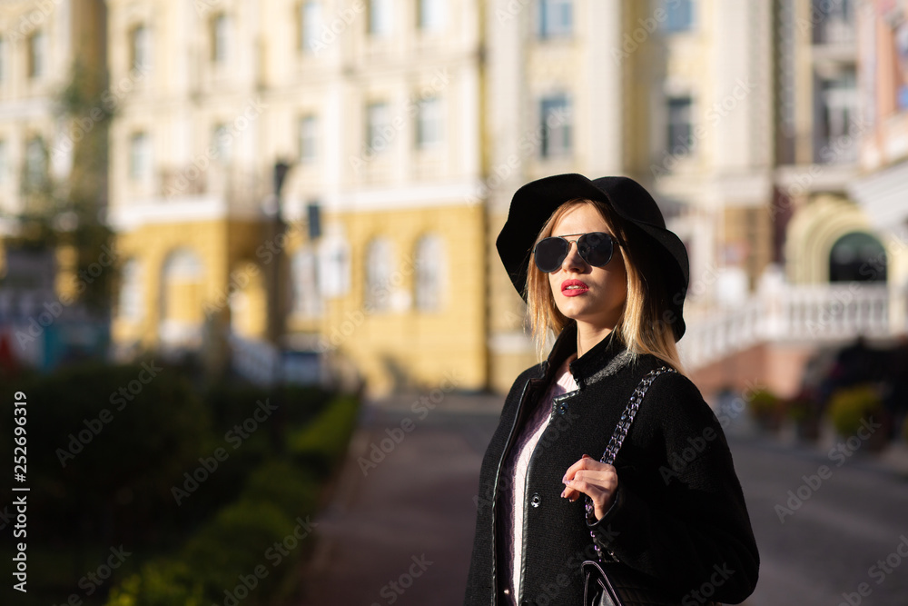 Street portrait of stunning blonde lady posing at the street with sun light. Empty space
