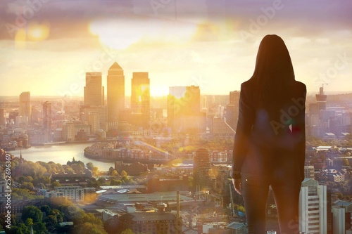 Young woman looking over the City of London at sun set. Future, new business opportunity and business success concept. photo