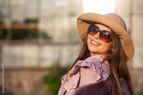 Street portrait of cheerful brunette model wears hat and sunglasses, enjoying warm weather. Empty space © vpavlyuk
