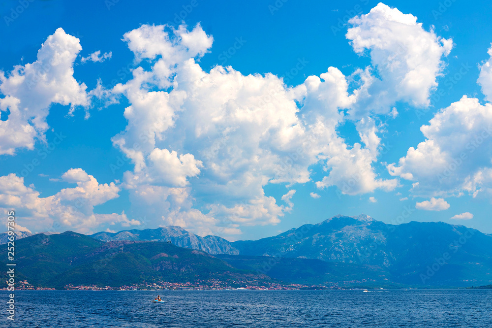 Incredible bright seascape. View of green wooded mountains and blue sea, blue sky and white clouds. Boka Kotorska Bay, Montenegro