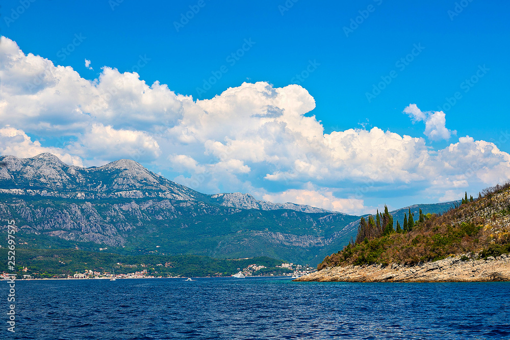 Incredible bright seascape. View of green wooded mountains and blue sea, blue sky and white clouds. Boka Kotorska Bay, Montenegro