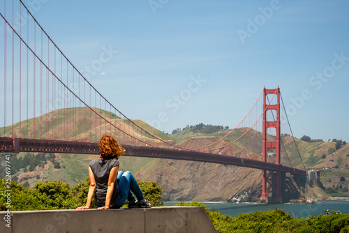 Young woman is watching Golden Gate bridge from a tourist point near the bridge in San Francisco, United States of America