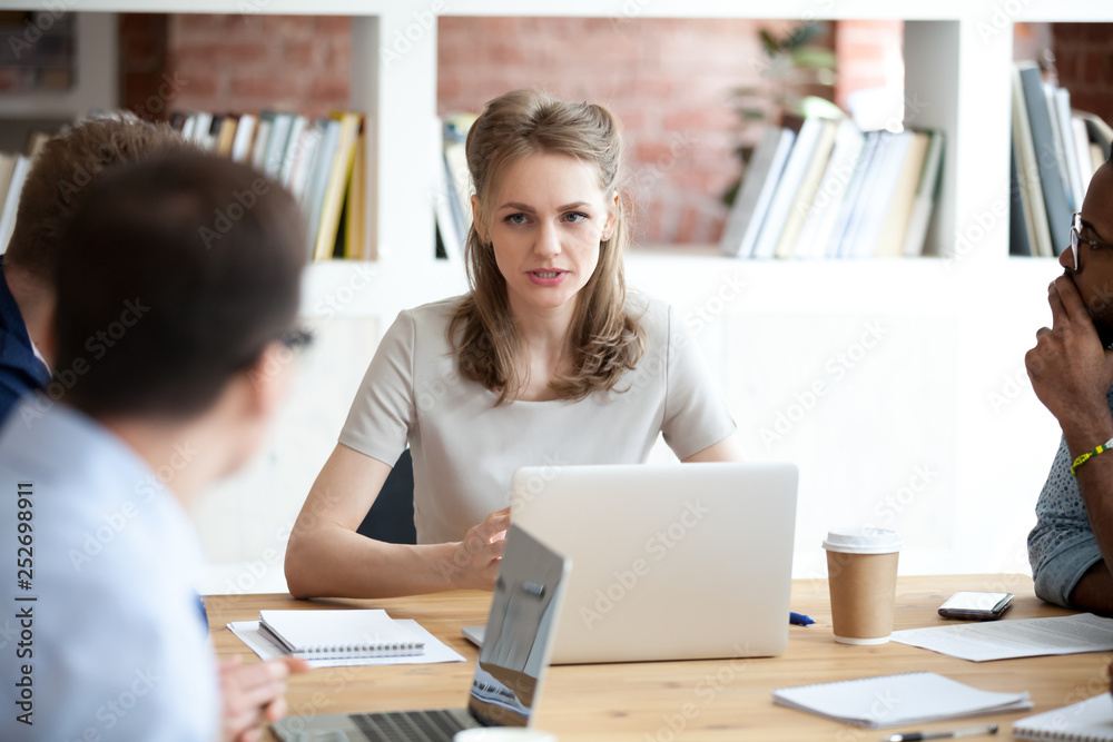 Serious boss female discussing project with employees sitting in office Serious boss female discussing project with employees sitting in office