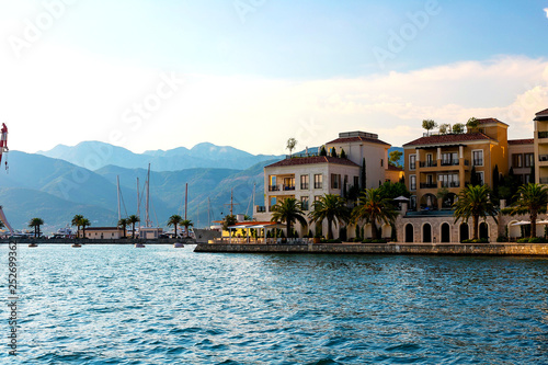 Scenic panoramic view of the historical city of Tivat, located in the Bay of Kotor on a sunny day at sunset in summer, the water reflects the rays of the sun, Montenegr