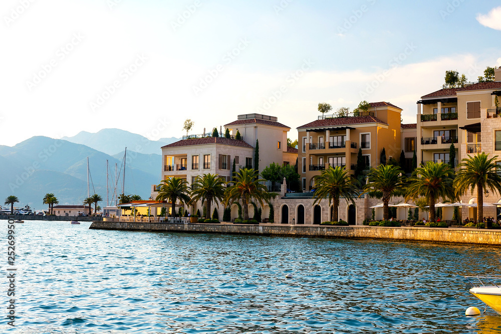 Scenic panoramic view of the historical city of Tivat, located in the Bay of Kotor on a sunny day at sunset in summer, the water reflects the rays of the sun, Montenegr