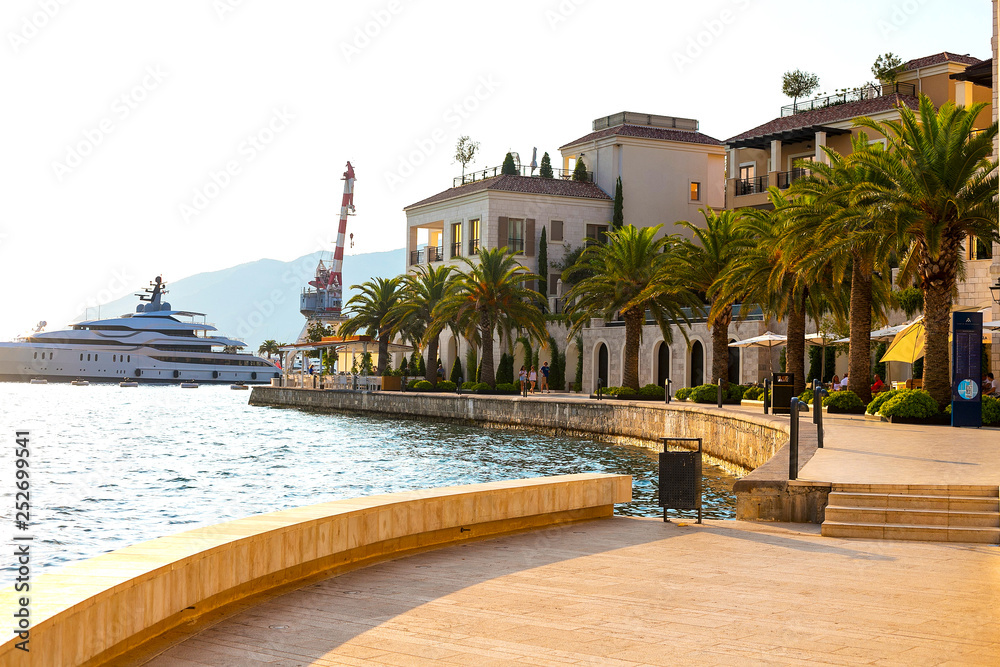 Scenic panoramic view of the historical city of Tivat, located in the Bay of Kotor on a sunny day at sunset in summer, the water reflects the rays of the sun, Montenegr