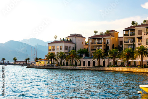 Fototapeta Naklejka Na Ścianę i Meble -  Scenic panoramic view of the historical city of Tivat, located in the Bay of Kotor on a sunny day at sunset in summer, the water reflects the rays of the sun, Montenegr