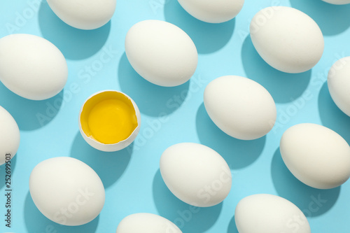 Flat lay composition with chicken eggs and half with yolk on color background, space for text