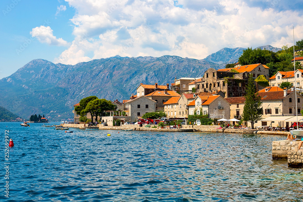 Scenic panoramic view of the historical city of Perast, located in the Bay of Kotor on a sunny day with blue sky and white clouds in summer, Montenegro, southern Europe