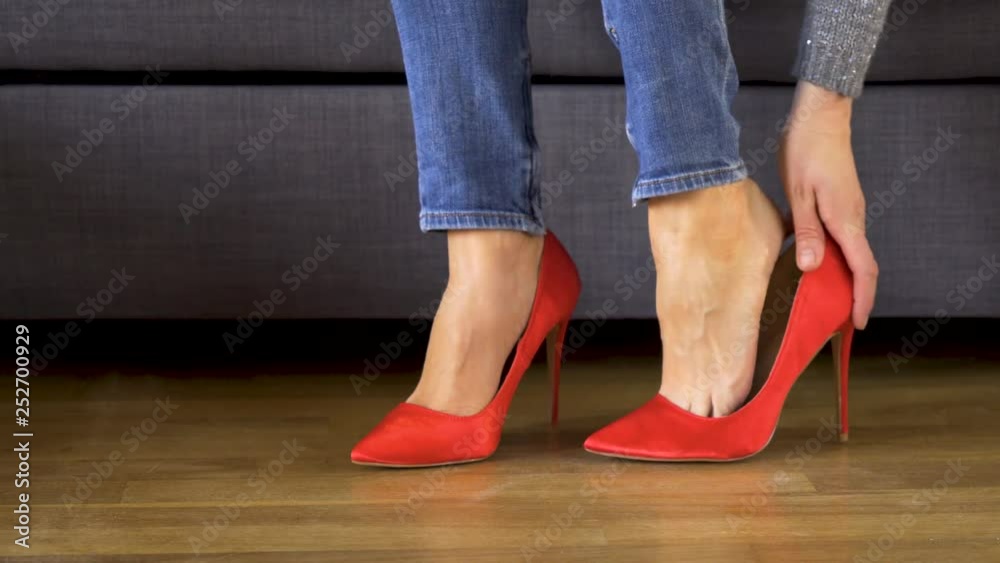 Beautiful sexy business woman takes off red high heels and massages painful legs in shoes after a hard day after work Beautiful sexy business woman takes off red high heels and massages painful legs in shoes after a hard day after work