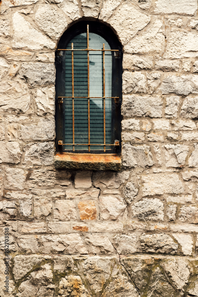 Obraz premium Window with arch and grille on stone wall