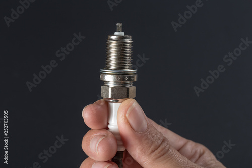  spark plug in hand on a dark background.