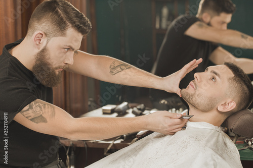 Checking his work. Professional barber checking his beard cut given to the client