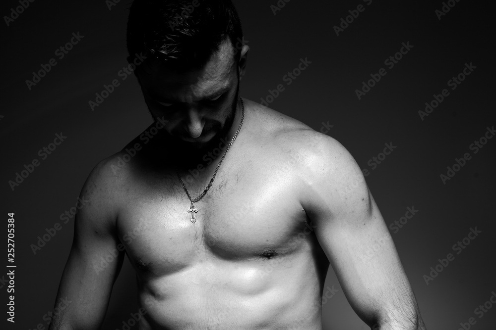 Fototapeta premium Black and white photo of a handsome and sporty guy close-up in studio