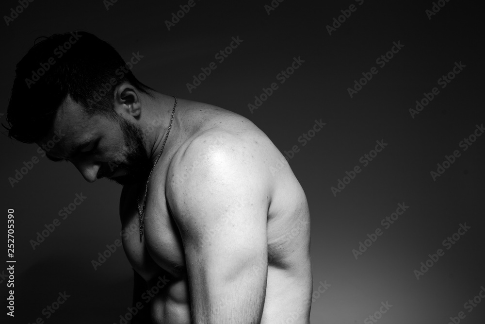 Naklejka premium Black and white photo of a handsome and sporty guy close-up in studio