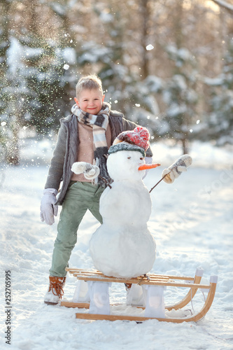 Сhild in the winter in the snow. To make a snowman. Sledging