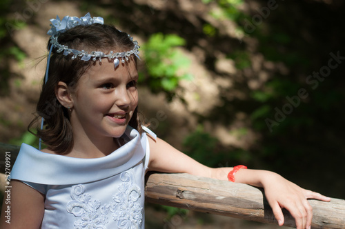 Portrait of cute little girl on white dress and wreath of first holy communion