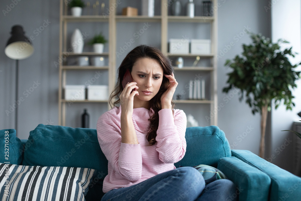 Smiling woman sitting on sofa in the living room having a phone call. Smiling woman sitting on sofa in the living room having a phone call.