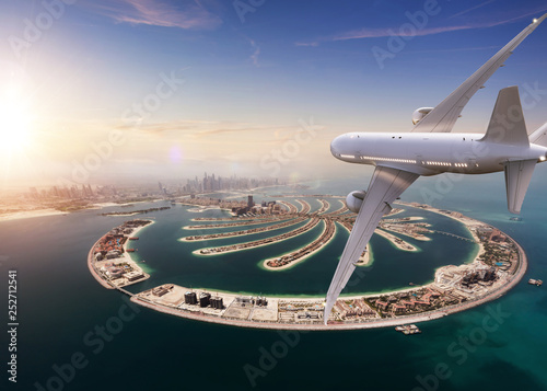 Commercial jet plane flying above Dubai city.