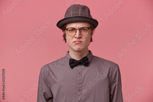 Quadro em tela Closeup portrait skeptical young man looking disrespectful, dissatisfied, pessimistic, full of distrust, isolated pink background