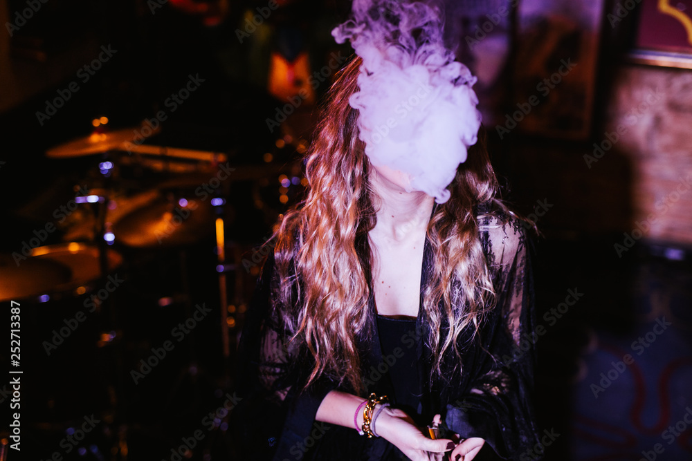 Fototapeta premium Young girl to vape in the disco