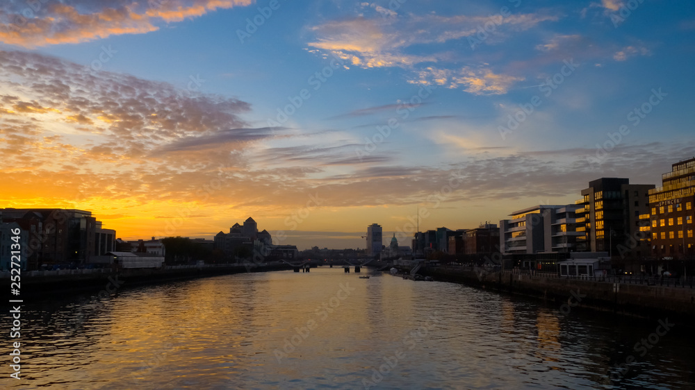 Spectacular sunset over River Liffey in Dublin, Ireland with blue orange gradient sky and dramatic clouds