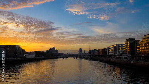 Spectacular sunset over River Liffey in Dublin, Ireland with blue orange gradient sky and dramatic clouds