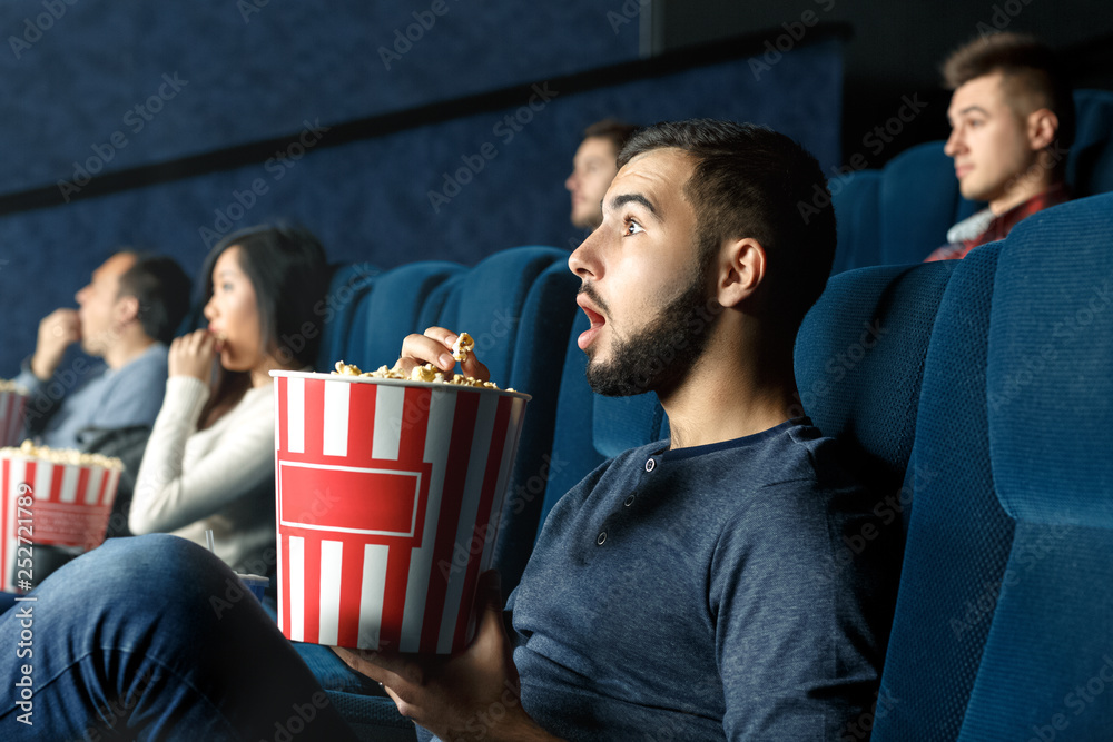 Deeply entertained. Horizontal portrait of a young man watching movie