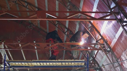 A welder welds huge metal construction in the hangar