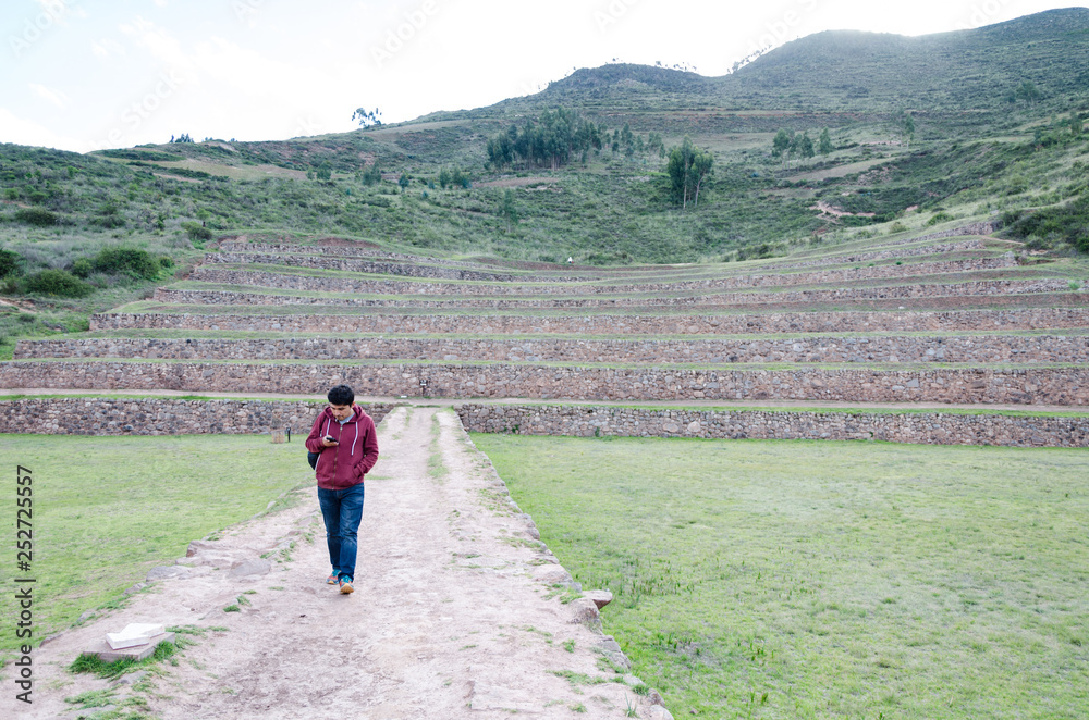 Agricultural terraces in the Sacred Valley. Tourist walking by Moray in Cusco, Sacred Valley, Peru.